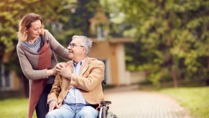 Frau geht mit älterem Mann im Rollstuhl spazieren (Foto: Lucky Business/shutterstock)