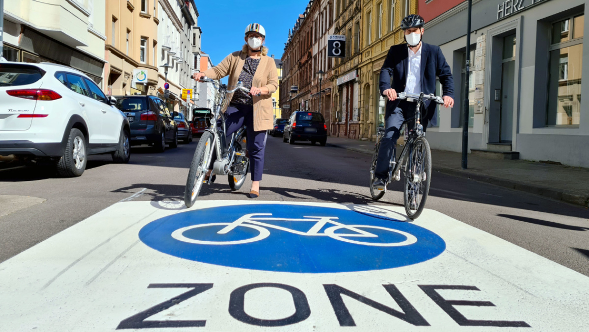 Anke Rehlinger und Uwe Conradt in der Fahrradzone im Nauwieser Viertel. Beide sitzen auf einem Fahrrad.