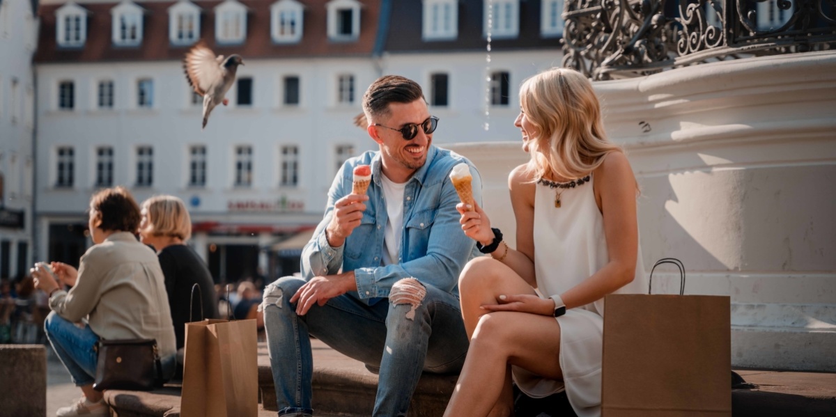 Shopping im Sommer Paar isst Eis während es am Marktbrunnen sitzt