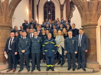 OB Uwe Conradt mit einer Gruppe Menschen, viele in THW Uniform, auf der Innentreppe des Rathauses.