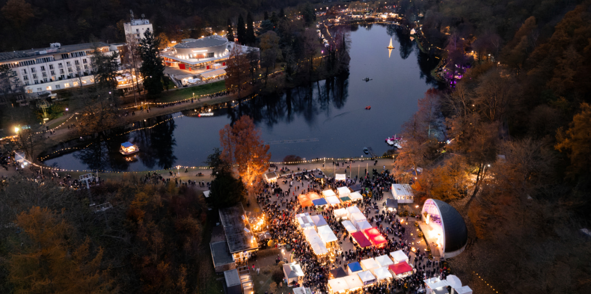 Blick von oben auf den Deutschmühlenweiher mit beleuchteten Ständen und der Seebühne