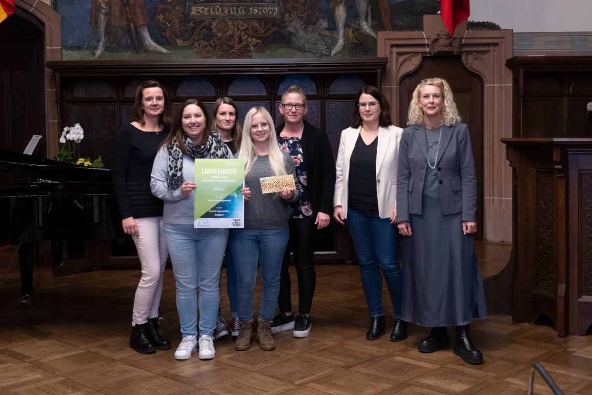 Preisübergabe an die Kita Malstatt. Zu sehen sind fünf Betreuerinnen der Grundschule, sowie zwei Jurymitglieder.