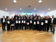 Eine Gruppe Personen in Uniform steht in Reihen und hält weiße Mappen fest