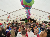 Viele bunt verkleidete Menschen feiern in einem mit Luftballons dekorierten Festzelt am Fetten Donnerstag 2025 im Rathaus St. Johann