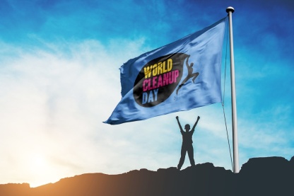 Rechts im Bild eine Flagge mit der Aufschrift World Cleanup Day, darunter die Silhouette eines Menschen, im Hintergrund Sonnenuntergang