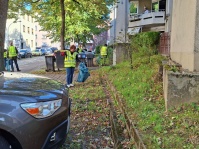 Menschen in Warnwesten sammeln Müll ein.