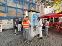 Menschen in Warnwesten reinigen einen Verteilerkasten 