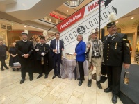 Eine Gruppe von Erwachsenen steht vor einer Programmtafel. Drei Männer tragen alte Bergmannuniformen