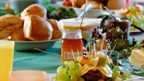Frühstückstafel mit bunten Gedecken, Brötchen und Butter 