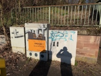 Drei weiße Versorgungskästen vor einer niedrigen Mauer mit Metallgeländer