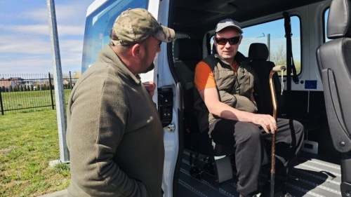 Zwei Männer vor einem weißen Bus, einer davon mobilitätseingeschränkt