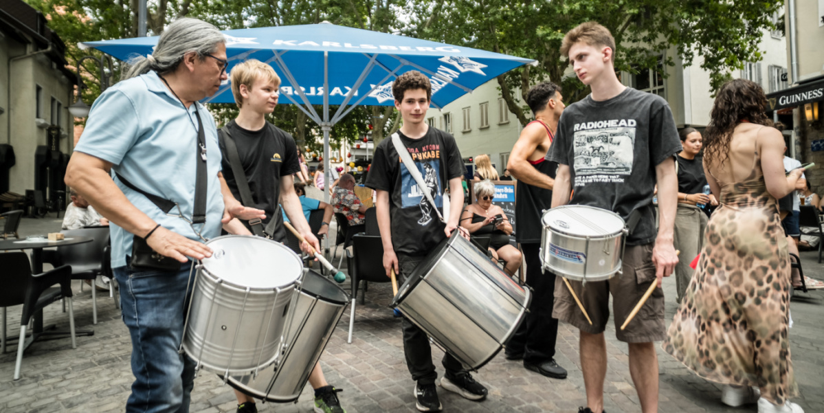 Drei Trommler mit Snaredrums unterhalten sich am Marktplatz
