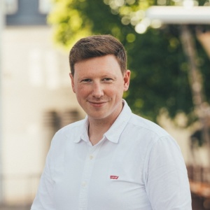 ein Mann in einem weißen Hemd lächelt in die Kamera