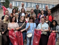 Gruppe von Menschen steht auf einer Treppe und hält rote Müllsäcke sowie Müllgreifer in den Händen.