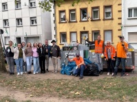 Eine Gruppe von Menschen bei einer Müllsammelaktion vor Glascontainern, daneben mehrere gefüllte Müllsäcke.