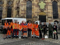 Mitarbeitende des ZKE mit Besen und Schaufeln bei einer Aufräumaktion vor der Ludwigskirche.