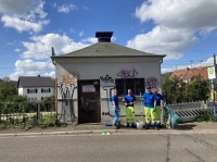 Vier Mitarbeitende der Stadtwerke Saarbrücken Netz AG mit Reinigungsutensilien vor einem mit Graffiti besprühten Gebäude.