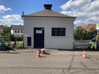 Gereinigtes Gebäude ohne Graffiti, davor stehen Reinigungsutensilien und zwei Warnkegel.
