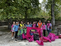Erwachsene und Kinder in bunten Warnwesten stehen mit gesammelten Müllsäcken und einem World-Cleanup-Day-Banner im Park.